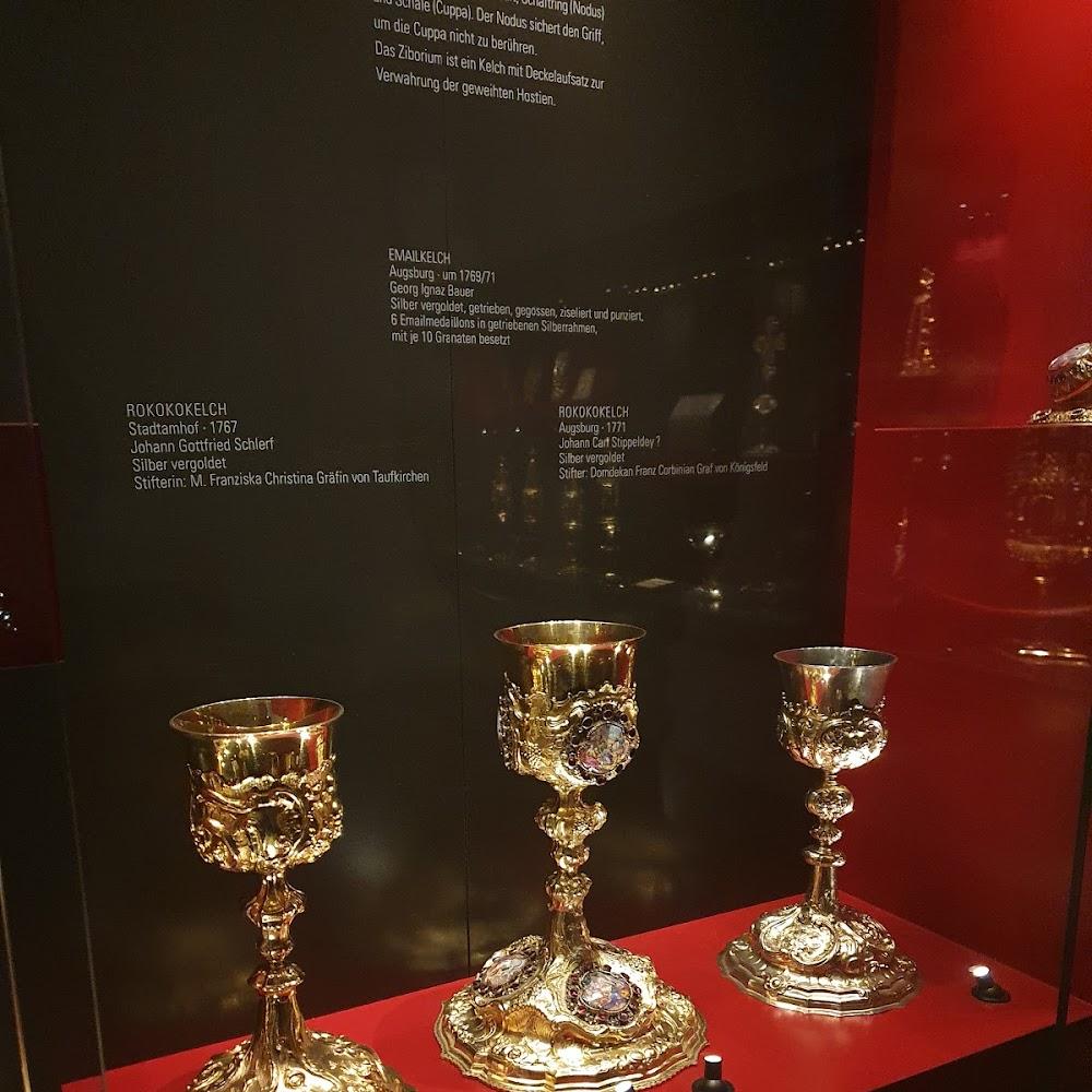 Three silver chalices on red velvet display.